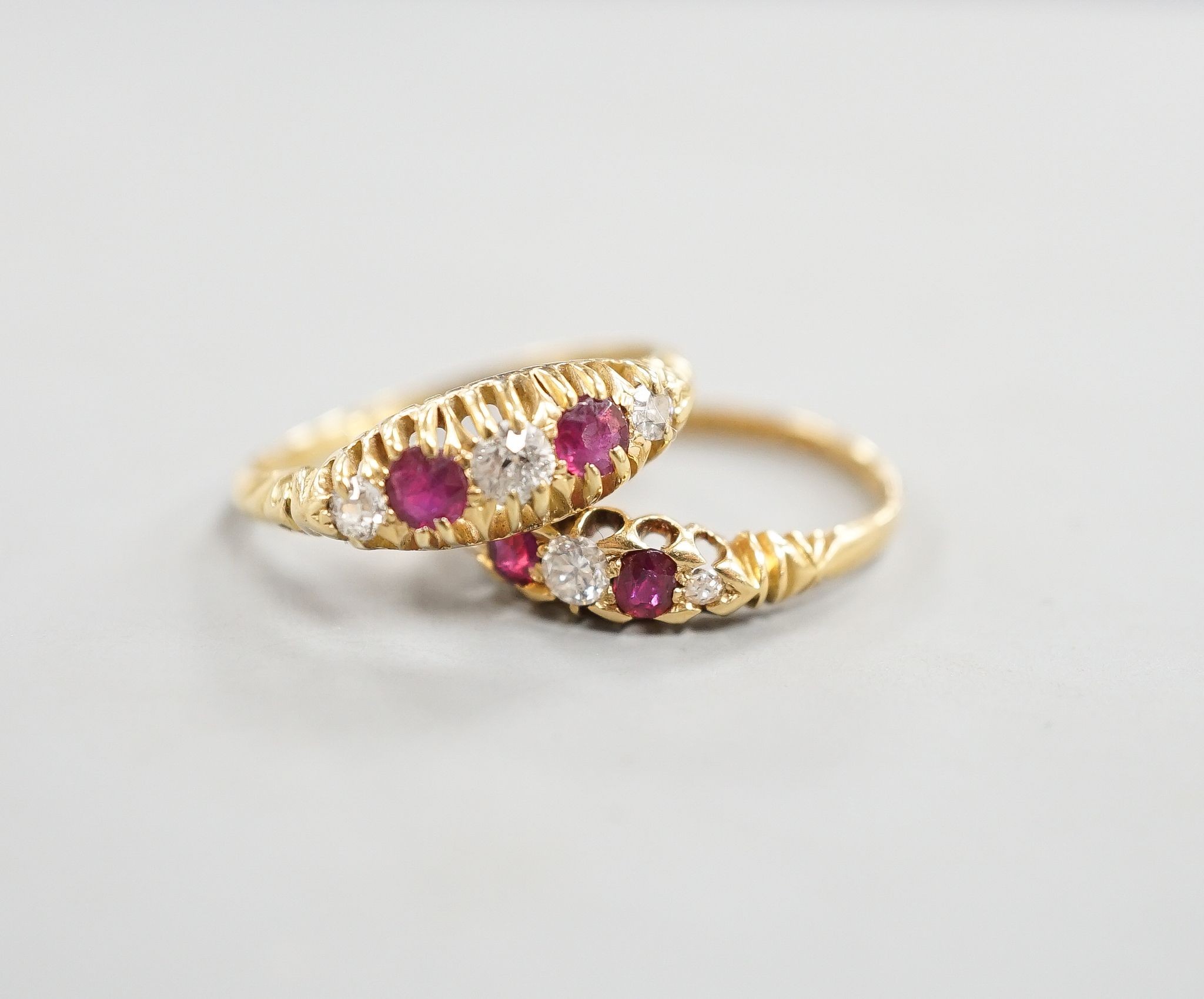 Two early 20th century 18ct gold, ruby and diamond five stone set half hoop rings, sizes m and P/Q, gross weight 5.1 grams.